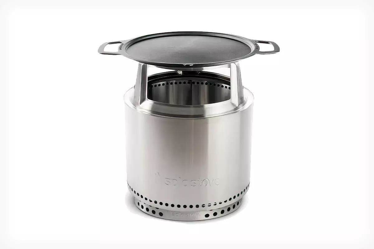 Studio photo of a silver Solo Stove with a cast iron griddle top.